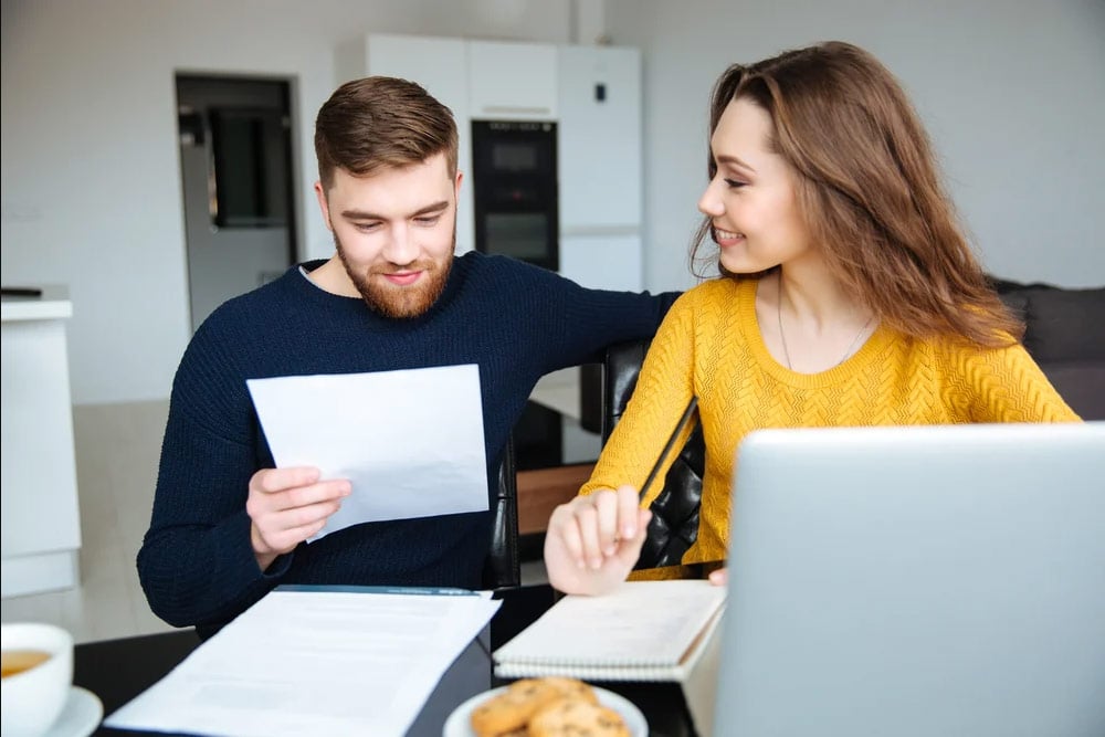 Happy-young-couple-calculating-bills-at-home